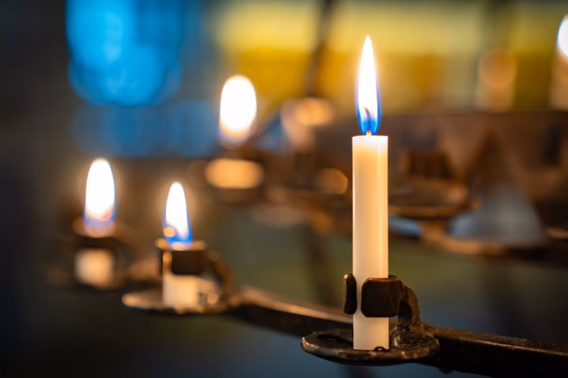 Brennende Kerzen zum Gedenken in einer Kirche (Symbolbild). Foto: IMAGO / Zoonar (Eva-Maria Pollich)
